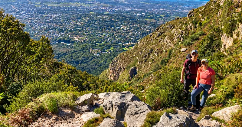 Una coppia su un sentiero di montagna roccioso con la città distesa sotto