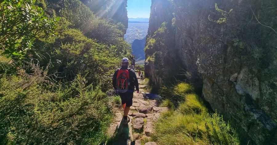 Ein Wanderer auf einem sonnigen Steinpfad in einer engen Schlucht zwischen hohen Felswänden